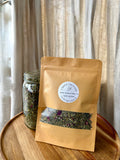 Tea package and jar on a wooden surface with a neutral curtain background